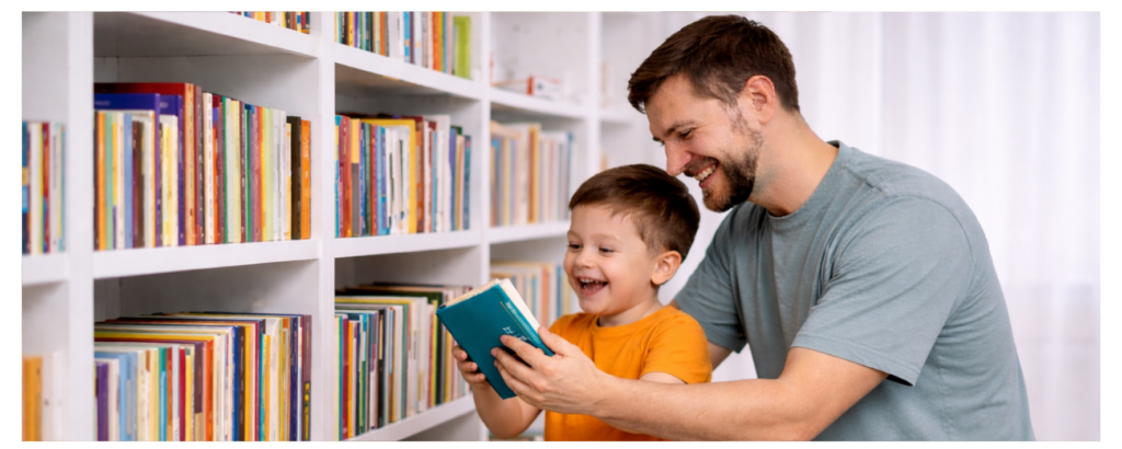 A father and his young son happily choosing and looking at a book together in front of a colorful bookshelf.